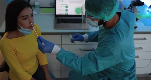 Healthcare worker with protective equipment performs coronavirus swab on young woman