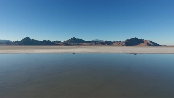 An aerial drone shot reveals smooth water covering the white salt of the Bonneville Salt Flats and d