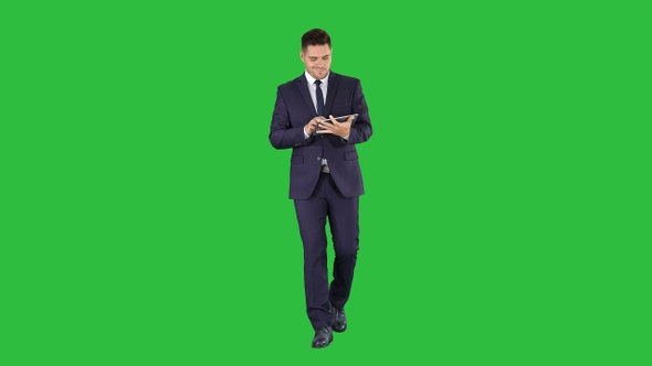 Man in suit walking and using digital tablet on a Green