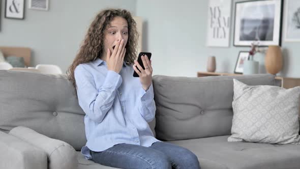 Relaxing Curly Hair Woman Cheering Success on Smartphone