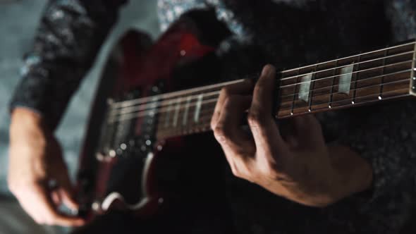 4K close-up of a man playing an electric guitar and changing the volume while holding a chord