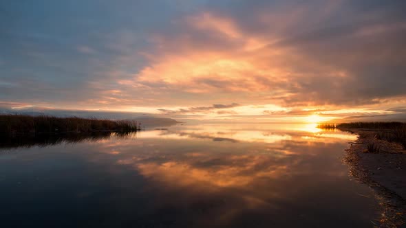 Time lapse over river as it flows into lake during colorful sunset