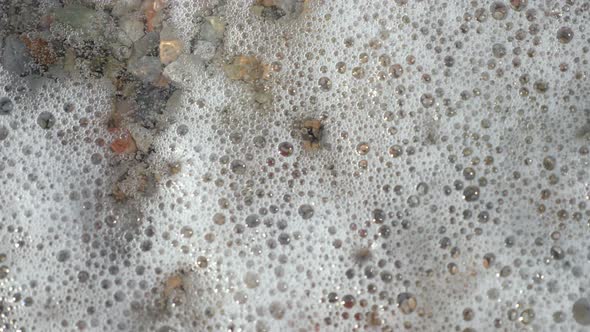 Close-up . Soft Waves, with White Foam Are Washed Ashore, on Pebble Beach. Beautiful , Multi-colored