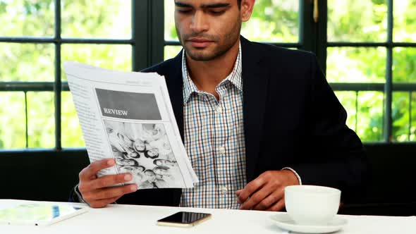 Businessman reading newspaper while having coffee 4k