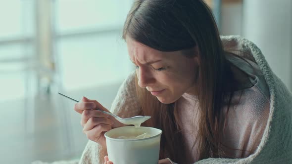 Heartbroken Young Woman Sitting on Sofa Crying Eating Ice Cream