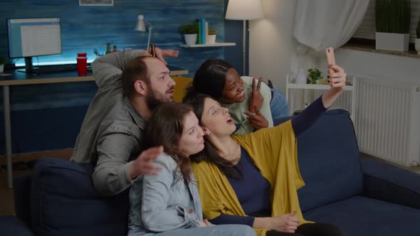 Excited Group of Multiracial Friends Sitting on Sofa During Joyful Party