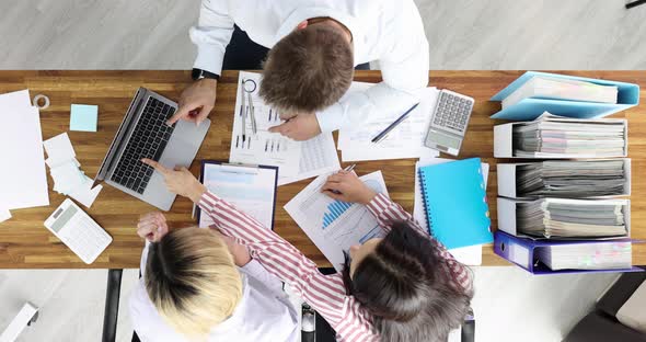 Group of Business People Rejoicing in Front of Laptop Screen and Documents with Charts Top View