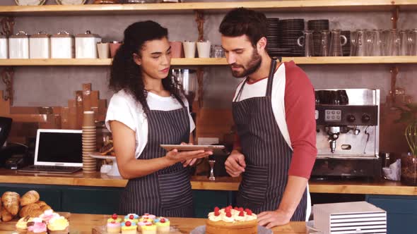 Smiling waiter and waitress using digital tablet at counter