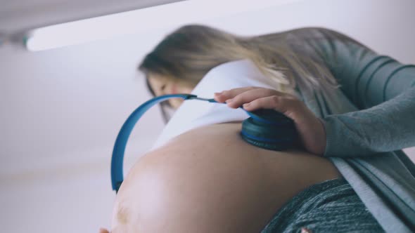 Nice Pregnant Woman Spends Time Listening to Music with Baby