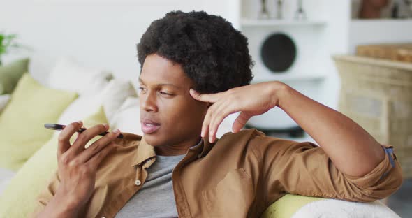 Happy african american man using smartphone at home