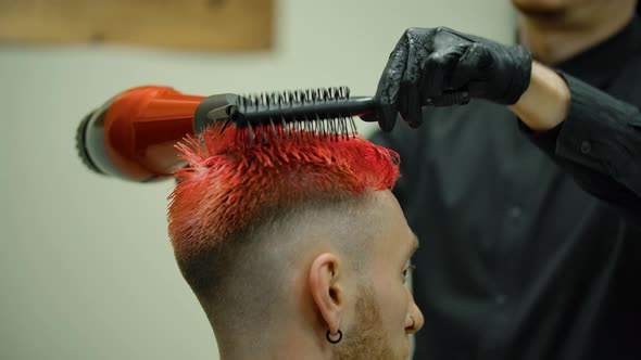 The Hairdresser Blows a Hairdryer and Combs the Guy's Colored Hair