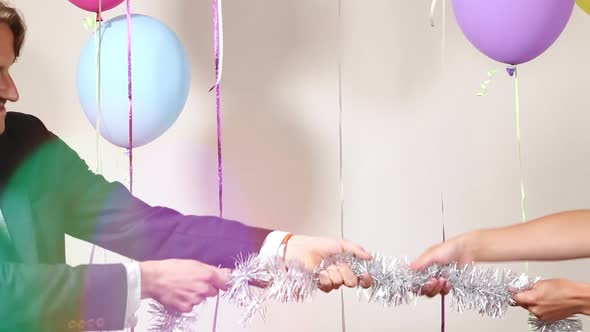 Attractive couple playing tug of war with shiny brace string