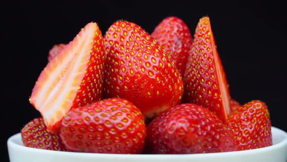 Strawberries without tails lie in white bowl or plate. It rotates