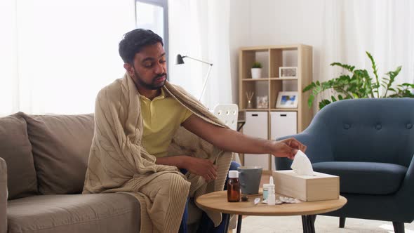 Sick Man Blowing Nose in Paper Tissue at Home