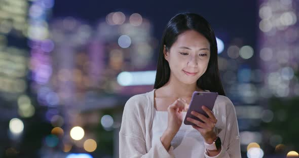 Woman use of mobile phone in city at night