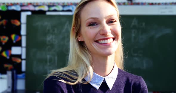 Portrait of happy teacher standing in classroom