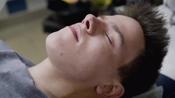 Beautician's Hand Wipes the Man's Face with Sponge During the Procedure