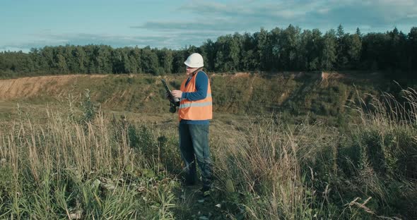 Working Engineer in White Helmet Next to a Sand Pit