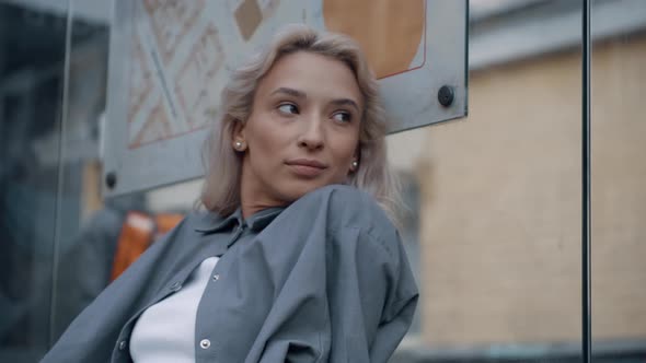 Casual Girl Bus Station Waiting for Ride in Big City Background