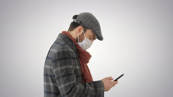 Stylish Man in Medical Mask Walking and Using Smart Phone on Gradient Background