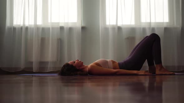 A Young Woman Fitness Instructor in Violet Sportswear Leggings and Top Stretching in the Gym Before