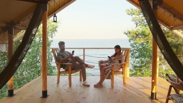 Couple Using Gadgets on Terrace by Lake