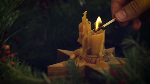 Hand lighting up candle in christmas wreath close up on rustic wooden table