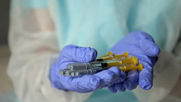 Hands of a Nurse in Protective Latex Gloves Hold Syringes Prepared for Vaccination