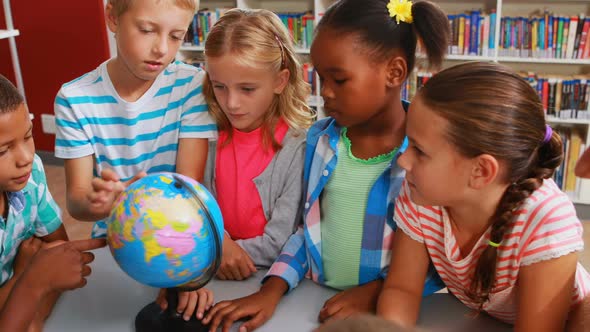 Kids and teacher looking at globe in library alt