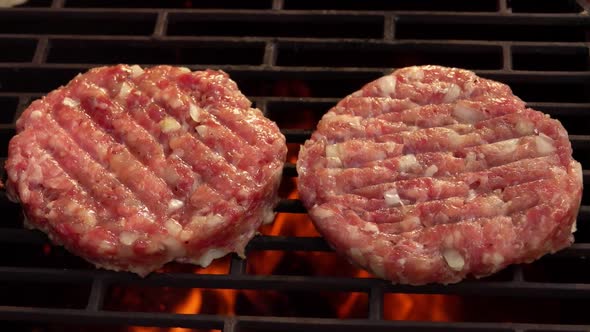Closeup of Two Juicy Meat Burger Cutlets with Onions Roasting Above the Fire