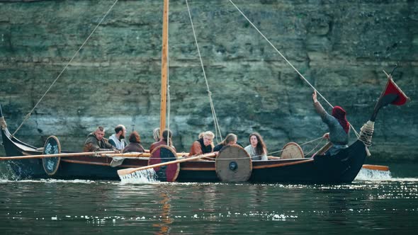 Vikings Sail on an Old Ship with a Lowered Sail on a Quiet River