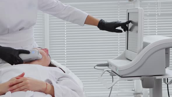 Body Massage Young Woman Having an Electric Massage Procedure on Her Face and the Therapist Pointing