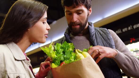 Smiling couple shopping for vegetables in organic section