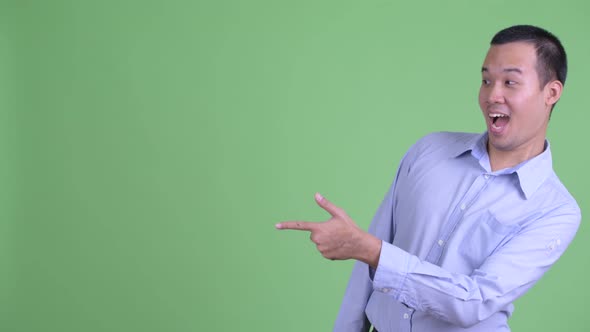Happy Asian Businessman Pointing Finger and Showing Something