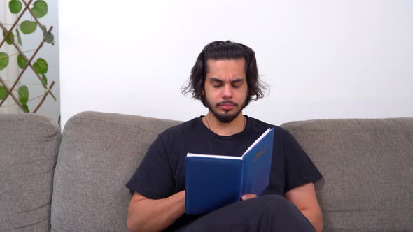 Sleepy Indian man reading a book late at night