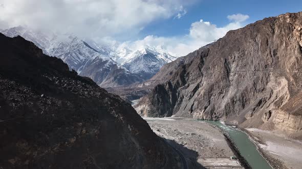 Drone Flying Through Shadow Of Valley To Reveal Snow Capped Mountains Of Hunza Valley. Dolly Forward