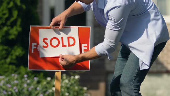 Young Man Setting Sold Sign Front of Building, Property Sell Service, Ownership
