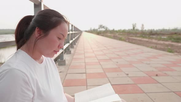 Asian short hair woman turning page of book while reading at outdoor