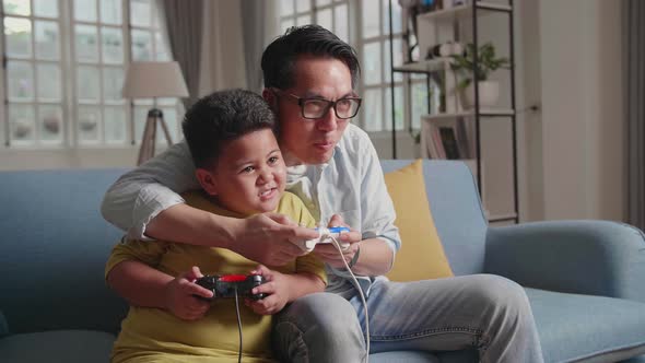 Asian Man And Son Having A Lot Of Fun While Playing Game At Home