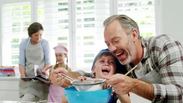 Father helping boy to filter flour using a strainer