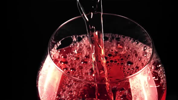 A Super Slow Motion Jet of Red Wine Pours Into a Glass of Air Bubbles