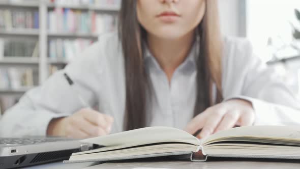 Selective Focus on a Book Female Student is Reading at the Library