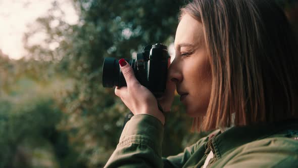 Girl taking picture at sunset in nature, hand held, mid shoot