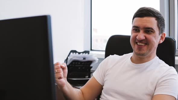 Young Handsome Guy Looking at PC Screen and Raising Fist Celebrating Success