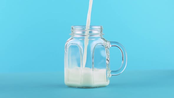 Milk Cold Beverage Drink Pooring Into Glass Jar Blue 