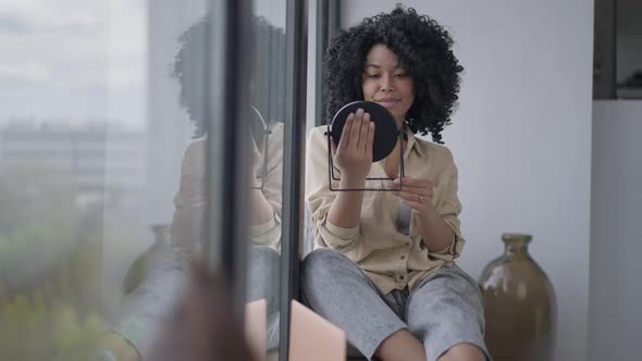 Wide Shot of Happy Smiling Gorgeous African American Woman Admiring Reflection in Hand Mirror