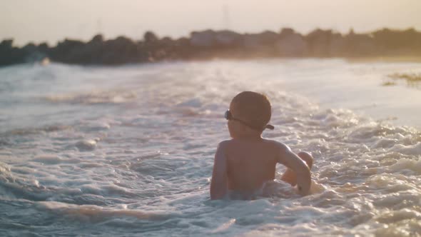 Child Bathing in the Sea Near Shore at Sunset