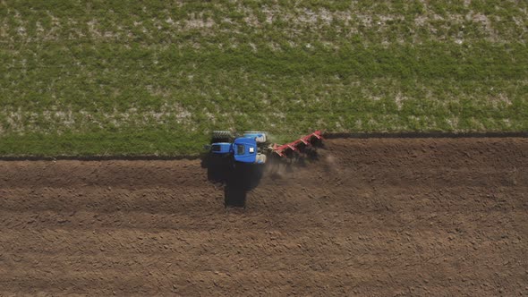 Aerial view of a tractor plowing a field in Lomellina, Po Valley, Italy.