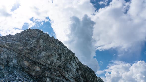 A Timelapse of Moving Clouds in the Sky with a Rocky Mountain Top in the Foreground