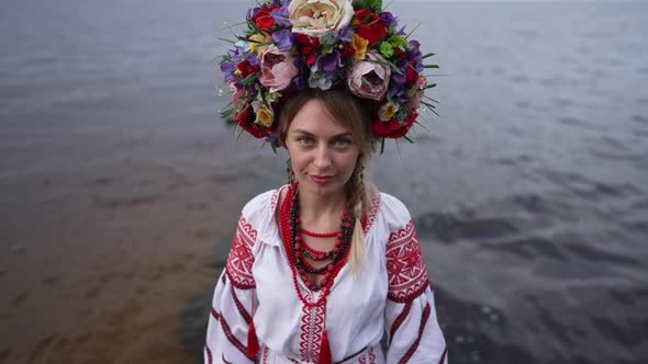 Portrait of Beautiful Ukrainian Woman in Embroidered Dress and Head Wreath Raising Face Looking at